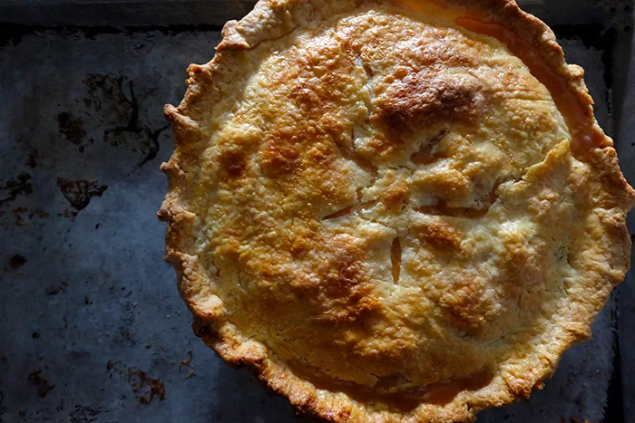 baked peach pie on baking sheet