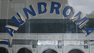 Photo of a window showing peeling letters spelling "laundromat".