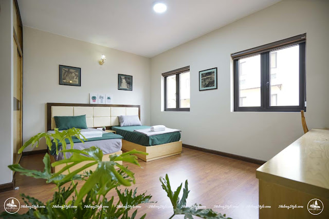 Phòng ngủ là 2 giường đơn với trang trí cây xanh và nội thất hiện đại