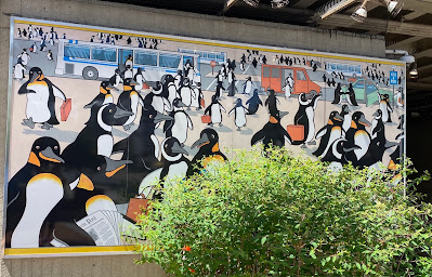 Photo of a digital mural of penguins on their morning commute.