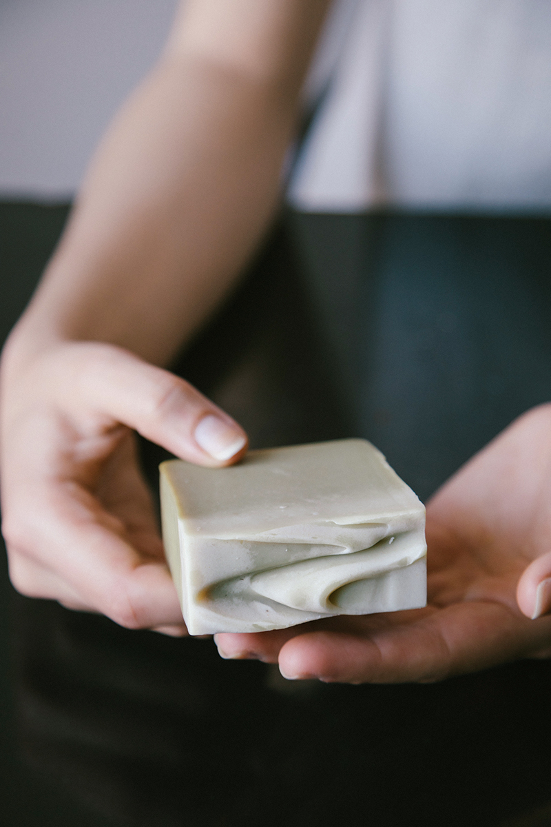 a close-up of woman's hand holding a bar of handmade soap