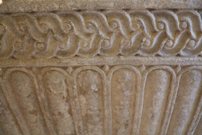 Sculptural detail of a large carved stone bowl with one pattern carved around the rim and another from rim to base