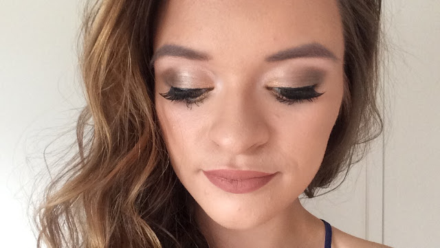 woman's face with brown smokey eye, false eyelashes, nude lip and hair curled on left