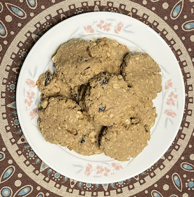 oatmeal raisin cookies on a white plate with a pink flower border, centered on a brown, tan, and turquoise round placemat