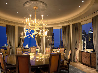 luxurious and stunning round room of dining room which includes round dining table and comfy chairs, stunning gold finished chandeliers, accent soft curtains and view to the city