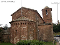 L'absis i el campanar de Sant Martí del Brull, i al fons a la dreta les restes del Castell del Brull