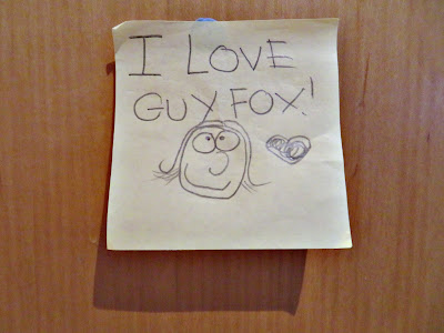 A post-it note with a smiley face and a child's handwriting stating, "I love Guy Fox!"