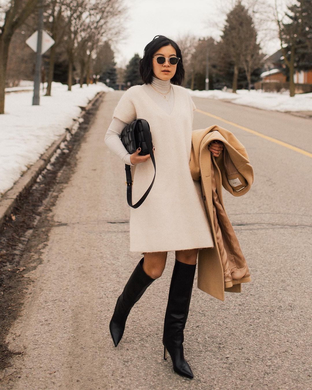 Here's How to Elevate Your Sweaterdress This Fall — @jessundecided Instagram outfit idea with a white sweater dress, layered turtleneck, camel coat, and black knee-high boots with pointed toe