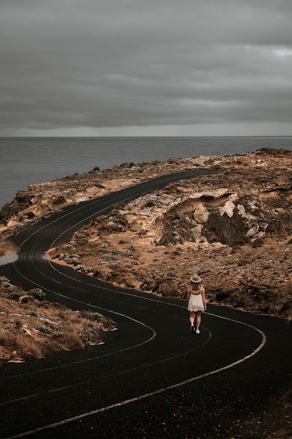 Mujer con braga blanca caminando sola por un camino rocoso