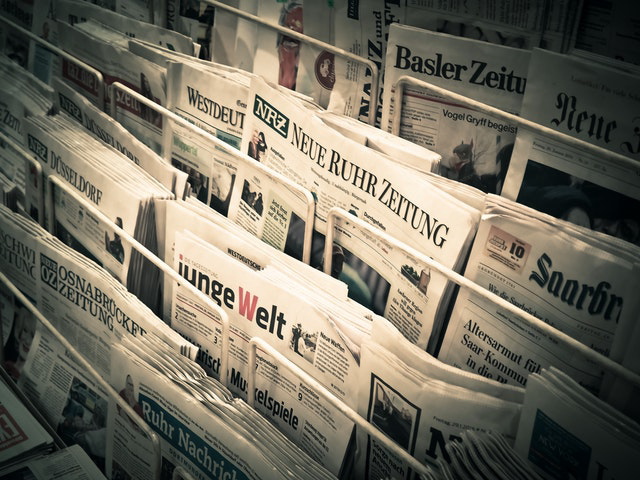 A news stand with newspapers being sold.