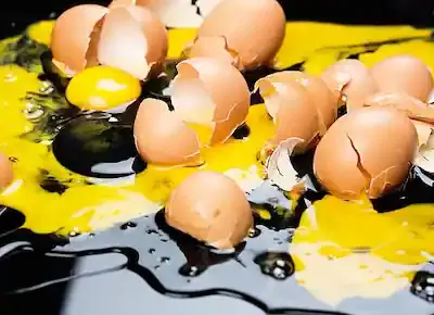 مجموعة من البيض المكسور الذي سال منه البياض والصفار على الأرض