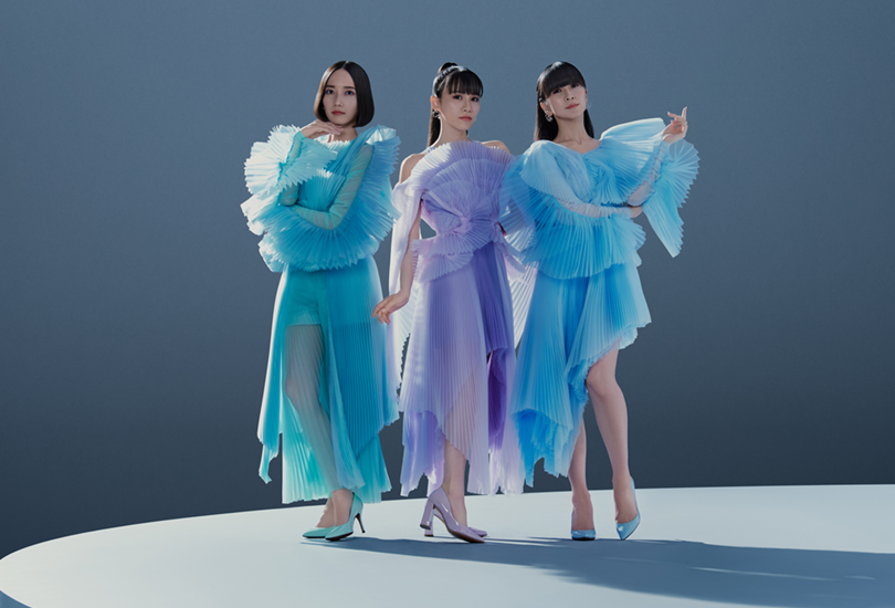A promotional shot of Perfume [From Left to Right: Nocchi, a-chan, Kashiyuka] for their single “Moon”. Featuring Perfume in pastel colour tulle dresses, stood on a a large circular platform.