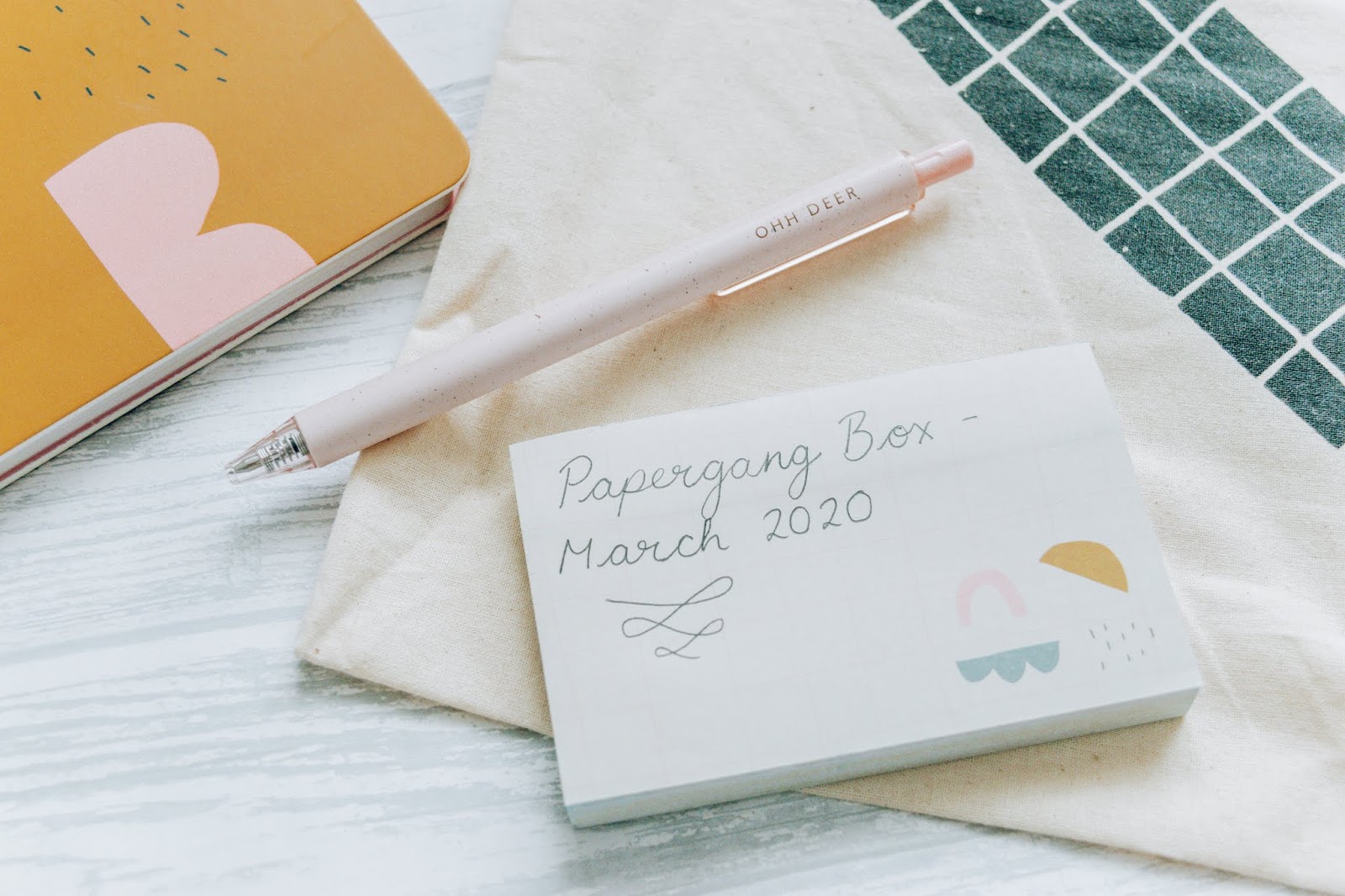 Beige sticky notes with geometric shapes and black writing on with a pink eggshell pen sitting on top.