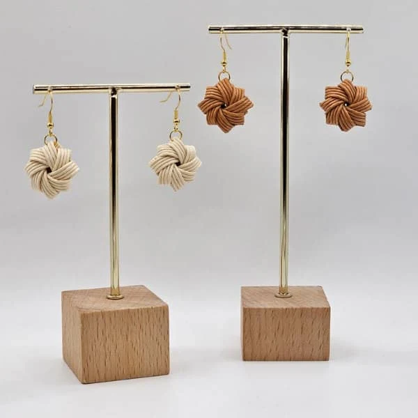 two pairs of woven paper earrings on stands with wood block bases