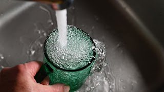 A person filling up a green glass with water from a sink | Countertop reverse osmosis system