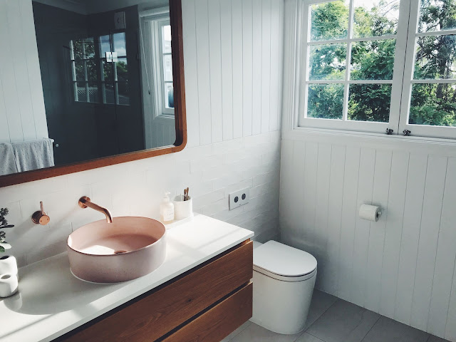 Powder room with vessel sink and toilet with white wood paneled walls.