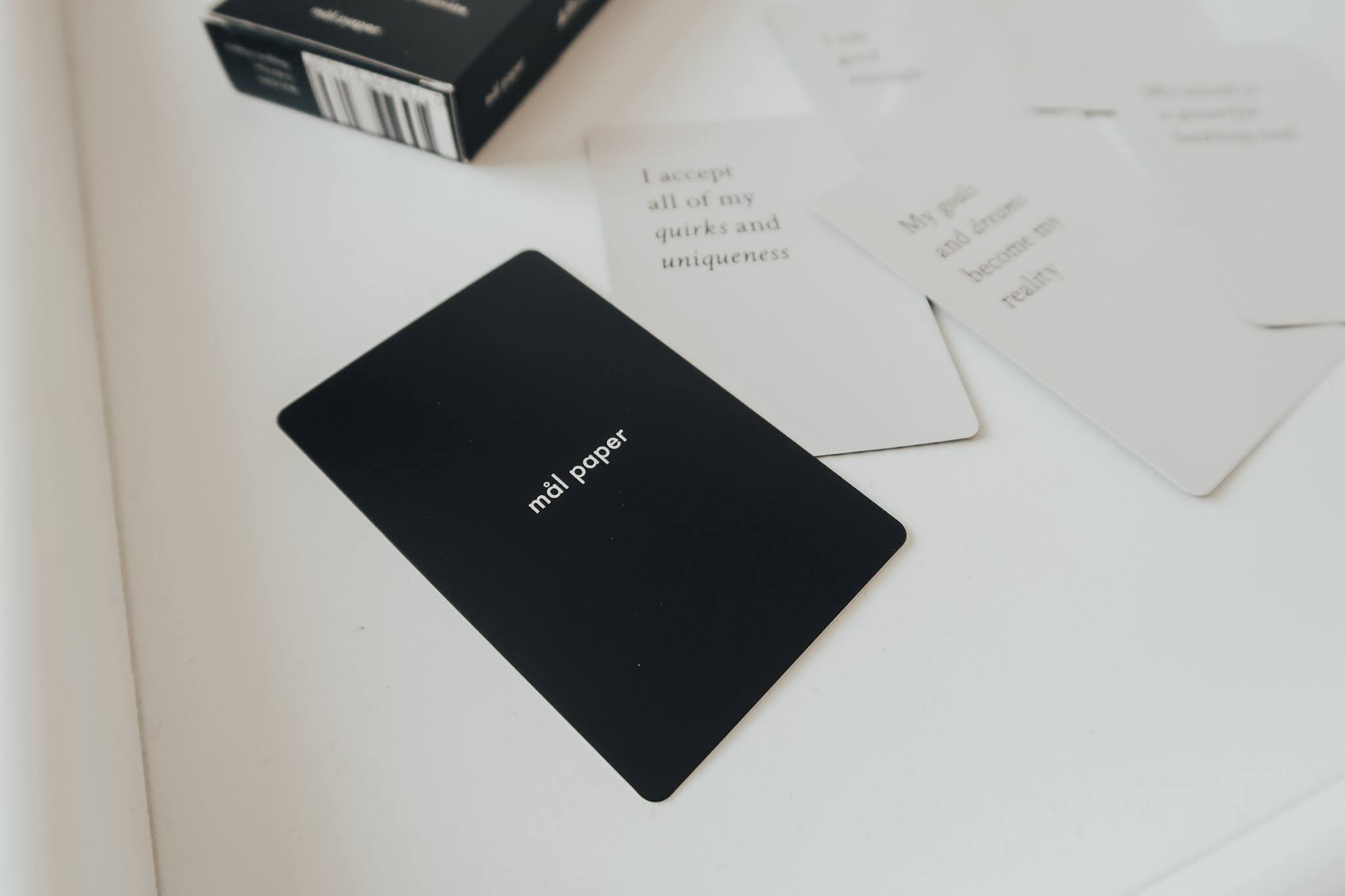 A black affirmation card box on a white tray.