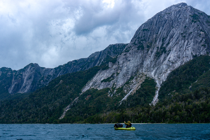 The picture shows the mountains and a packraft on  the lake.