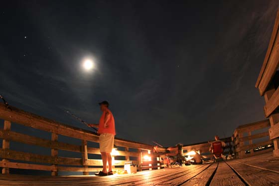 Fishing at night under the moon and stars on a pier in Isle of Palms, South Carolina.