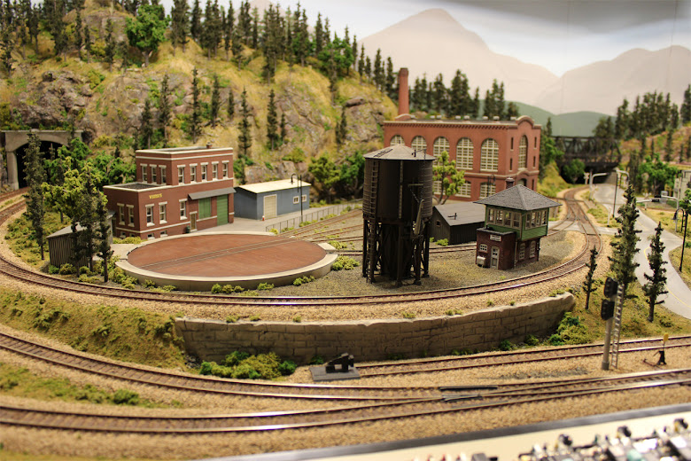 Completed industrial scene including rail yard, water tower, turn table, signal tower and various model building kits