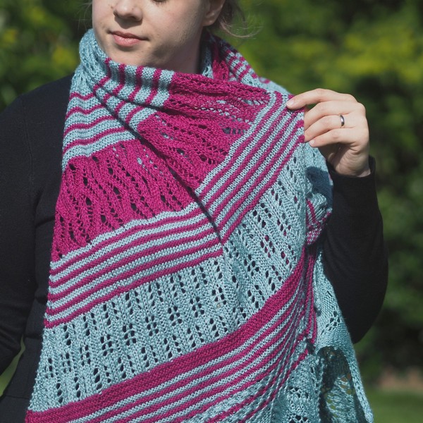 woman wearing seafoam and magenta lace wrap around neck and holding out part of the wrap