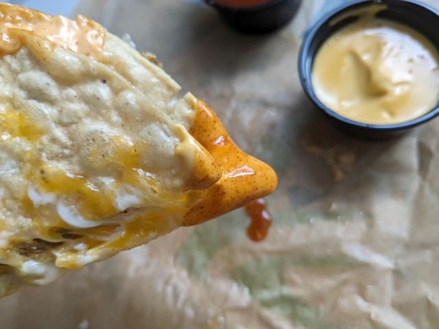 Taco Bell Grilled Cheese Dipping Taco dipped in cheese and red sauce.