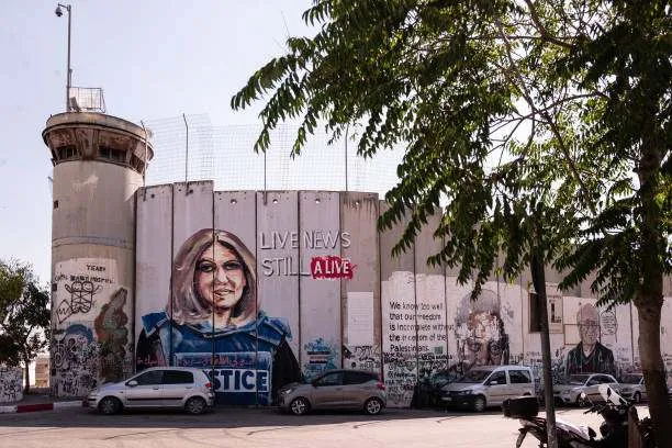 The more than 700-kilometer-long wall separating Israel from Palestine is seen from the city of Bethlehem, featuring a mural of journalist Shireen Abu Akleh, who was killed by Israeli soldiers on May 11, 2022, while covering an Israeli army operation in a refugee camp in Jenin. Photo by Alessandro Levati/Getty Images