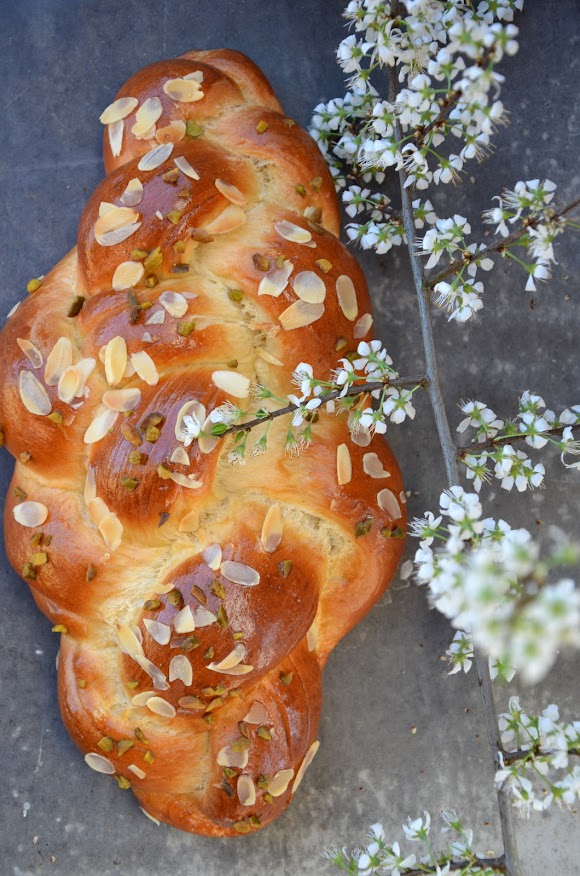 Fertig gebackener, goldgelb glänzender Osterbrioche auf blaugrauem Untergrund.