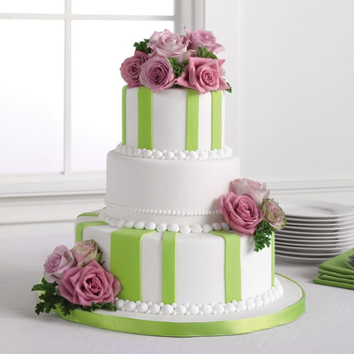 Four tier white square wedding cake with green ribbons and fuchsia gerbera