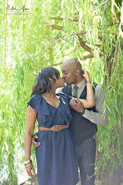 engaged couple kissing underneath a willow tree