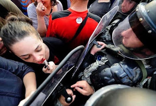 WOMAN APPLYING LIPSTICK WHILE PROTESTING