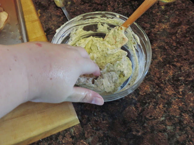 The herb butter being scooped out of the bowl.