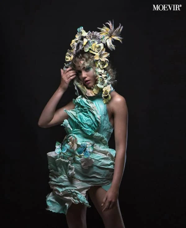 young female model dressed in elaborate aqua and yellow paper outfit and paper flower headpiece