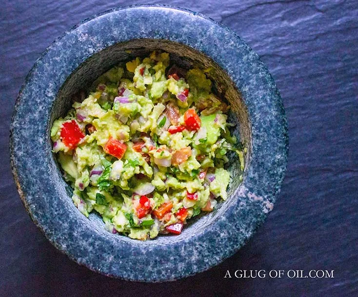 Homemade guacamole pictured in a granite bowl.