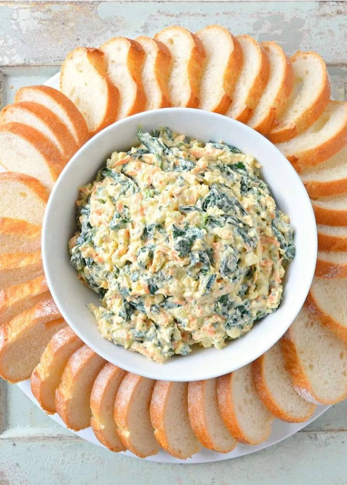Homemade Spinach Dip Recipe from scratch in a white bowl with bageutte around the edge.