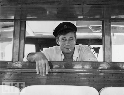 Yves Montand regards his passengers on board his yacht at Cannes during a 