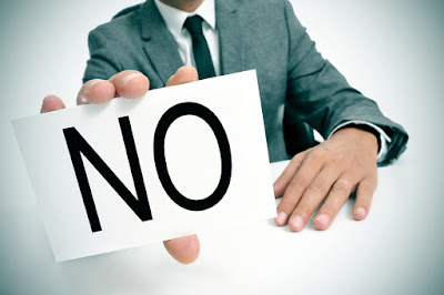 A business man holds a large sign that simply says NO
