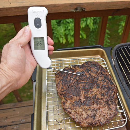 Using a Thermapen to take the internal temperature of a resting flank steak