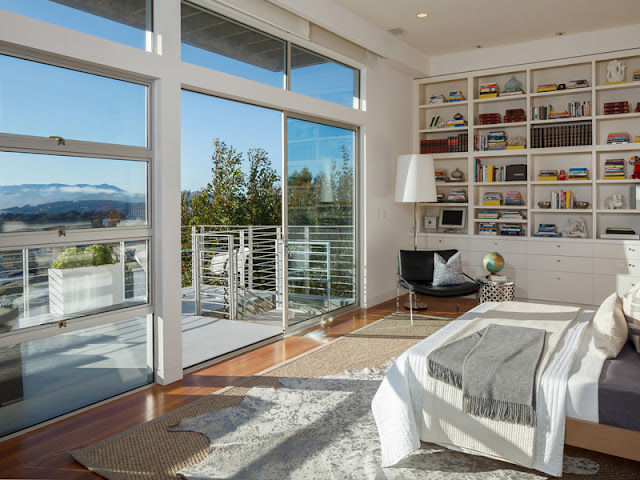 Picture of another contemporary bedroom with huge windows and large book shelf 