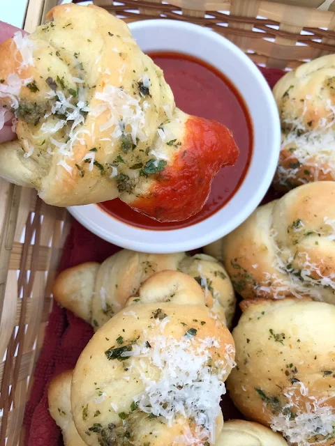 Garlic knot being dipped into pasta sauce.