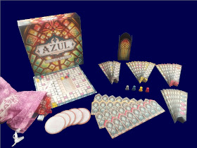 The game components alongside the game box. There is a pink bag with translucent tiles in various colours that resemble small pieces of glass, about the size and shape of starburst candies. There are several round tiles, a scoring board, long rectangular tiles with notched bottoms that come in four sets of eight, and wide rectangular tiles with notches along the top designed for the long pieces to fit into. There are also four plastic pawns and a tall but skinny cardboard box decorated to look like a tower of stained glass windows..