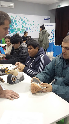 En la imagen, dos alumnos de la escuela, identificando las máscaras y sus características a través del tacto, acompañados por las descripciones verbales del guía del museo.