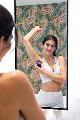 Mujer aplicándose desodorante delante de un espejo