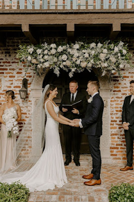 bride and groom holding hands at altar in front of casa feliz