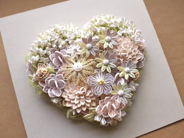 heart-shaped pastel quilled flower arrangement on white background paper