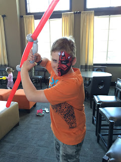 Boy Holding a light saber balloon with a Darth Maul Face