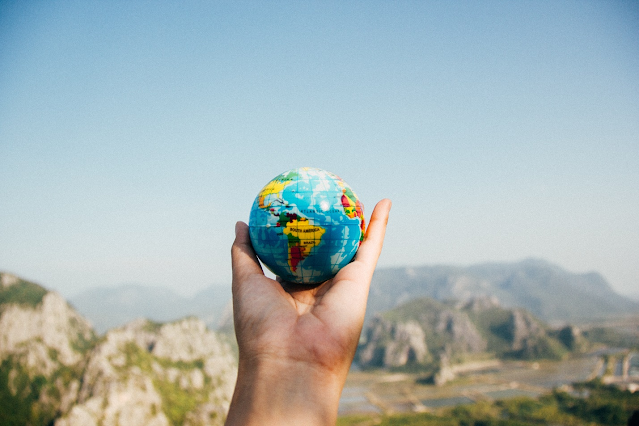 a person holding a globe near the mountains