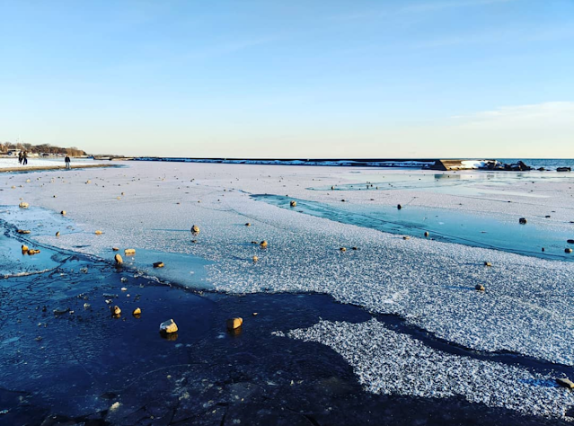 Frozen lake with snow on top and a blue sky in the background