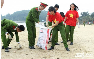 Chiến sỹ công an trẻ mặc áo cờ đỏ sao vàng làm sạch môi trường biển