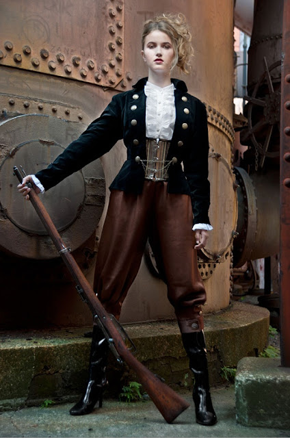 Woman wearing steampunk clothing consisting of jacket, blouse, corset, pants, boots and gun